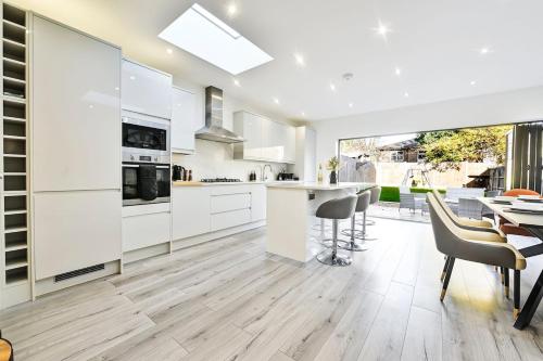 a kitchen with white cabinets and a table and chairs at Stylish House Near Wembley Stadium in London