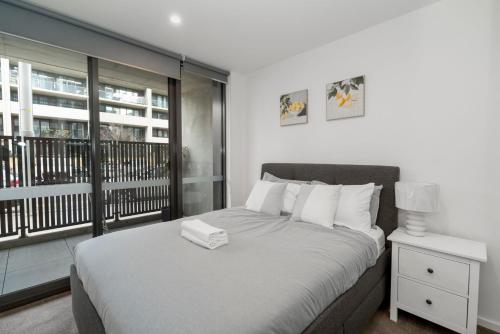 ein Schlafzimmer mit großem Bett und Balkon in der Unterkunft Modern 2Br Ground Level City Retreat with Parking in Braddon
