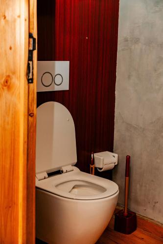 a white toilet in a bathroom with red curtain at Ndare Eco Ville in Kigali