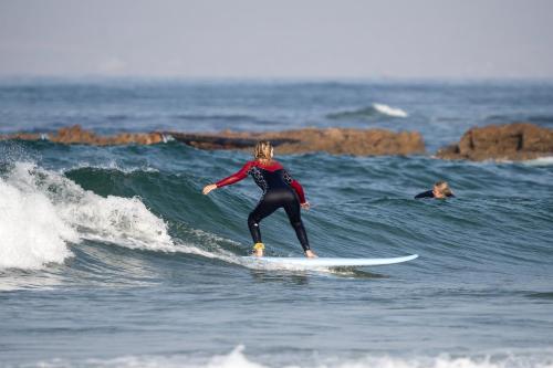a woman riding a wave on a surfboard in the ocean at Namaste Lodge Experience in Taghazout