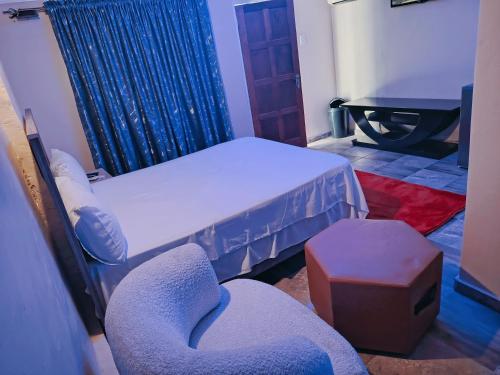 a room with two beds and a stool and a chair at Wampex Guest House in Rustenburg