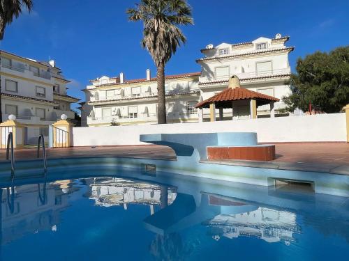 a pool of water in front of a building at Elegant 3-bed family beach house with large pool area in Praia da Areia Branca