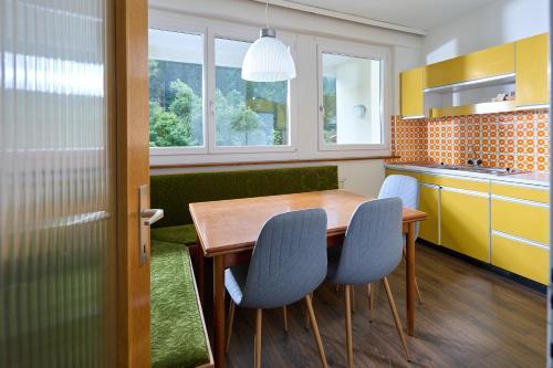 a kitchen with a wooden table and blue chairs at Fabis Apartment Gaschurn in Größing