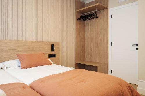 a bedroom with a bed with an orange pillow on it at Hostal Pico de Noro in Ribeira