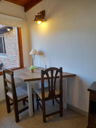 a dining room table with two chairs and a table and a lamp at Curahue Apart Hotel in Tandil