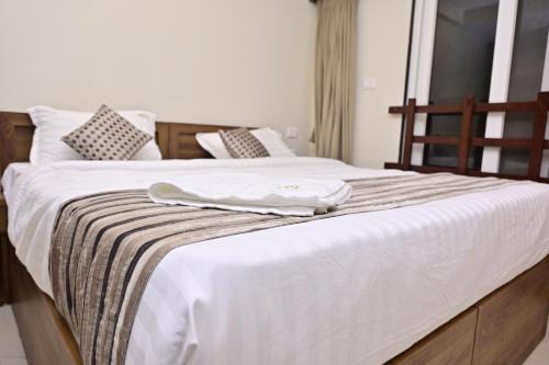 a white bed with a towel on top of it at Hotel Noble Nook, 100 Ft Road, Indiranagar in Bengaluru