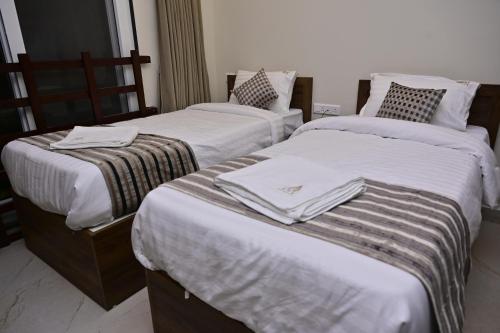two beds in a hotel room with towels on them at Hotel Noble Nook, 100 Ft Road, Indiranagar in Bengaluru