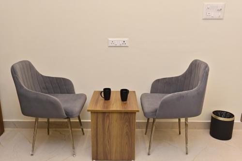 two chairs and a table in a room at Hotel Noble Nook, 100 Ft Road, Indiranagar in Bengaluru