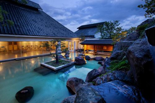 a swimming pool with rocks in front of a building at Shiragiku in Beppu