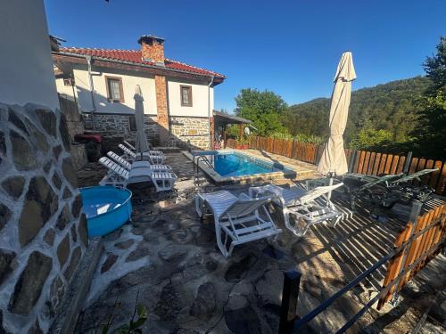 a patio with chairs and a pool and a house at Къща за гости Ножери in Tryavna