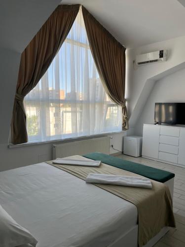 a bedroom with a bed with a large window at City Hotel Bucharest in Bucharest
