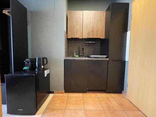 a kitchen with a black refrigerator and wooden cabinets at M13 - Innenstadt Studio in Stuttgart Zentrum in Stuttgart