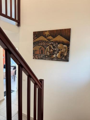 a painting hanging on a wall next to a staircase at Villa Dézil in Les Anses-dʼArlets