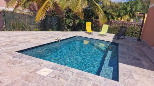 a swimming pool with two chairs and a swimming pool at Villa Dézil in Les Anses-dʼArlets