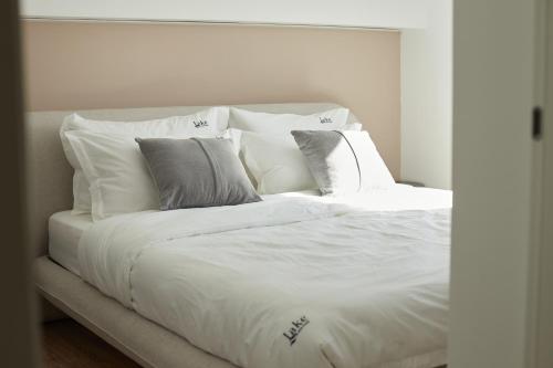 a white bed with white sheets and pillows at Lake side story in Frumuşani