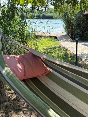 a hammock with a pillow sitting on it next to a lake at Viola Horgász-és Vendégház in Tiszaug
