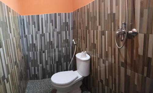 a bathroom with a toilet and a shower at Dev Guesthouse and Restaurant in Senaru