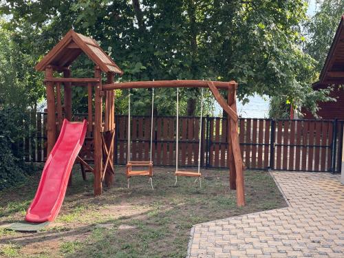 a wooden playground with a slide and a chair at Viola Horgász-és Vendégház in Tiszaug