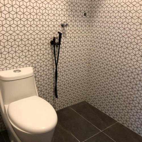a bathroom with a toilet and a white wall at Seribu malam homestay in Bukit Payong
