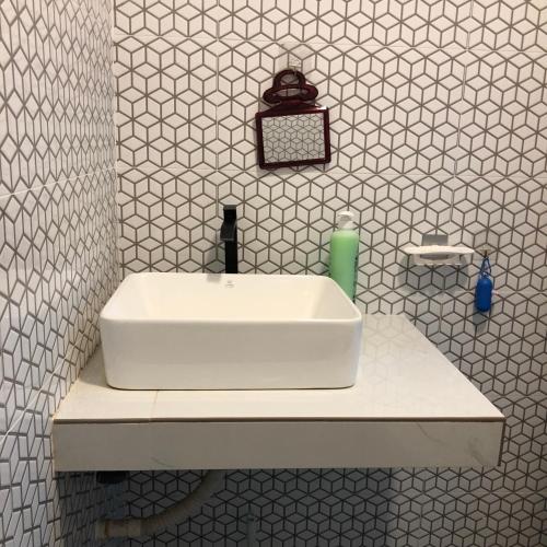 a white sink in a white tiled bathroom at Seribu malam homestay in Bukit Payong