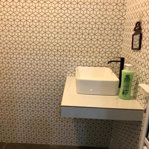 a bathroom with a white sink and white tiles at Seribu malam homestay in Bukit Payong