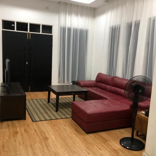 a living room with a red couch and a table at Seribu malam homestay in Bukit Payong