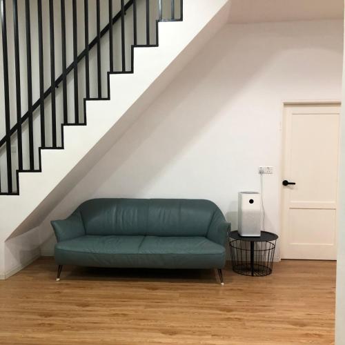 a green couch in a living room under a staircase at Seribu malam homestay in Bukit Payong