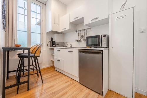 a kitchen with a refrigerator and a table with a microwave at Paris Secret Spot - Loft Unique aux portes de Paris in Gentilly