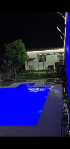 a blue swimming pool at night in front of a house at شاليهات Chalets in Būbādī