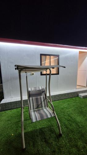 a chair sitting under a table in the grass at شاليهات Chalets in Būbādī