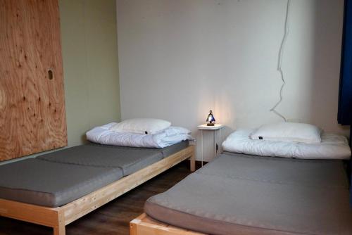 a room with two beds and a lamp on a table at Tug-B Bar & Hostel in Otaru