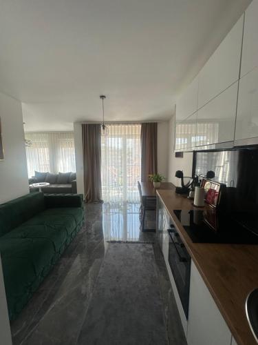 a living room with a green couch and a kitchen at Star apartman 3 in Novi Pazar