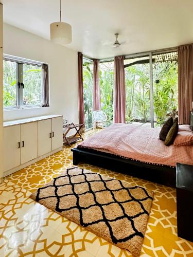 a bedroom with a bed and a large window at Siboney House by evaddo in Siolim