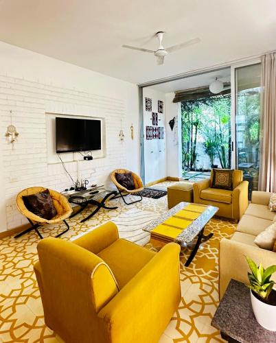 a living room with yellow furniture and a tv at Siboney House by evaddo in Siolim