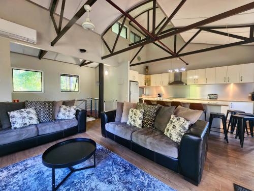 a living room with two couches and a kitchen at Villa 521 Kingfisher Bay Fraser Island in Kingfisher Bay