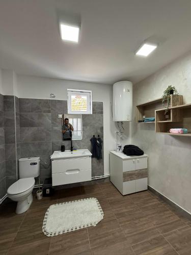 a person taking a picture of a bathroom with a toilet and sink at Apartman MATEA in Pirot
