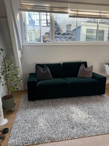 a green couch in a living room with a window at OHotellMe City Apartments Rotterdam in Rotterdam