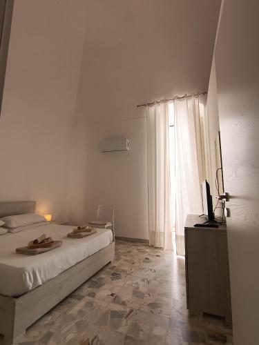 a white bedroom with a bed and a television at Casa Morrone Residence in Corato