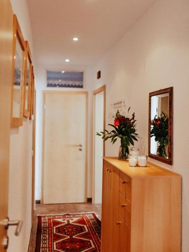 a hallway with a dresser with a mirror and a door at Ferienwohnungen Krampert in Bad Kissingen