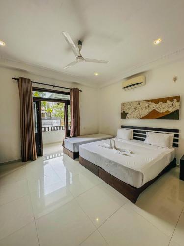a bedroom with two beds and a ceiling fan at Sunrise Palace Negombo in Negombo