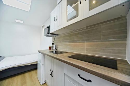 a kitchen with white cabinets and a sink at Chic Cosy - 10m2 Home in CR7 in Thornton Heath