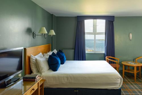 a bedroom with a bed with blue pillows and a window at Portrush Atlantic Hotel in Portrush