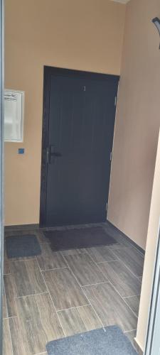 a large black door in a room with a tile floor at Žvejų gatvė 1 Telšiai in Telšiai