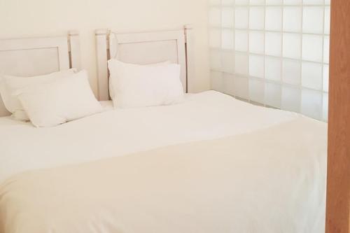a white bed with white sheets and pillows at Estréla da Luz CasaValerie studio with gym and indoor pool in Luz
