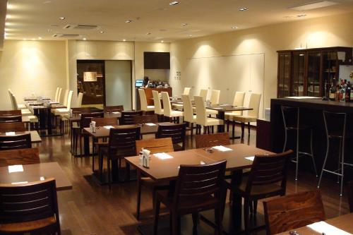 a restaurant with tables and chairs and a bar at Hotel Bestland in Tsukuba