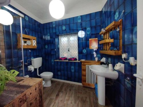 a blue tiled bathroom with a toilet and a sink at Ca' d'la nona casa con giardino in Agliano Terme