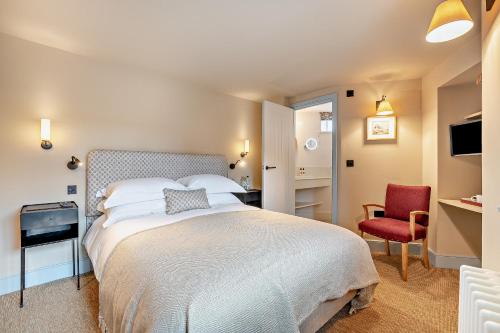 a bedroom with a large bed and a red chair at Cub Bedroom Two in Eastdean