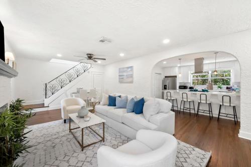 a white living room with a white couch and a kitchen at Cozy West Palm Beach Home l 10min to Municipal Beach and more! in West Palm Beach