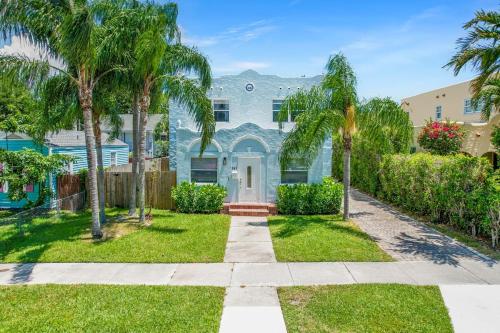 a blue house with palm trees in a yard at Cozy West Palm Beach Home l 10min to Municipal Beach and more! in West Palm Beach