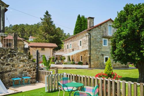 a garden with chairs and a table in front of a house at La casa de los Barbazanes in Brion